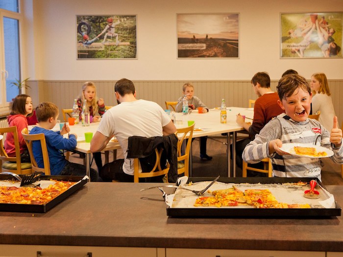Teilnehmer einer Kinder Jugendfreizeit essen Pizza