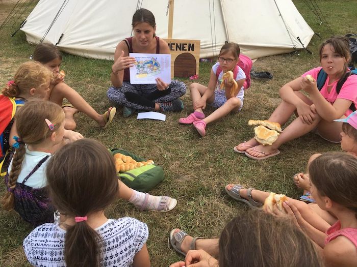 Teilnehmer einer Kinder und Jugendfreizeit sitzen draußen