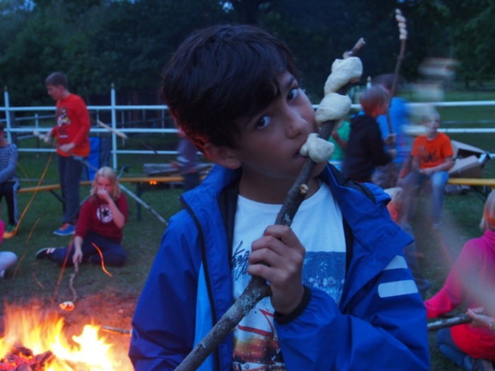 Teilnehmer einer Kinder und Jugendfreizeit essen Stockbrot