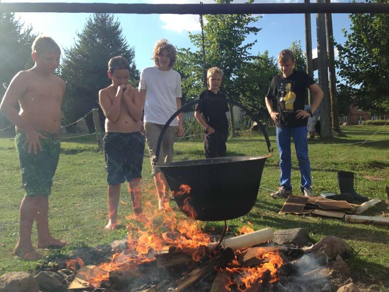 Kinder im Outdoor Camp stehen vor einem Topf über einem Lagerfeuer
