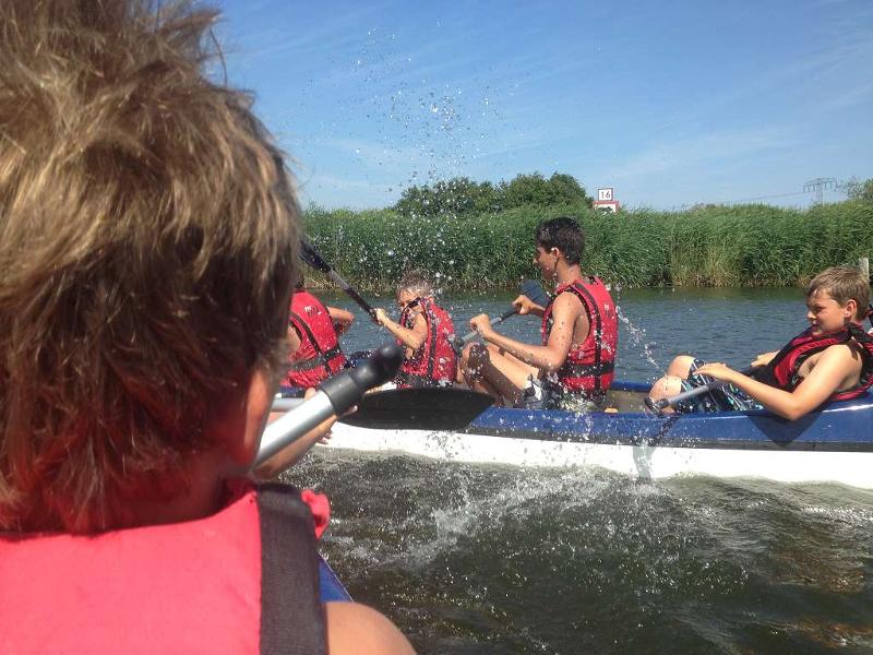 Teilnehmer eines Outdoorcamps fahren Kanu