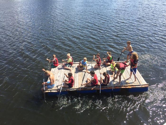 Kinder fahren während des Outdoorcamps auf einem Floß