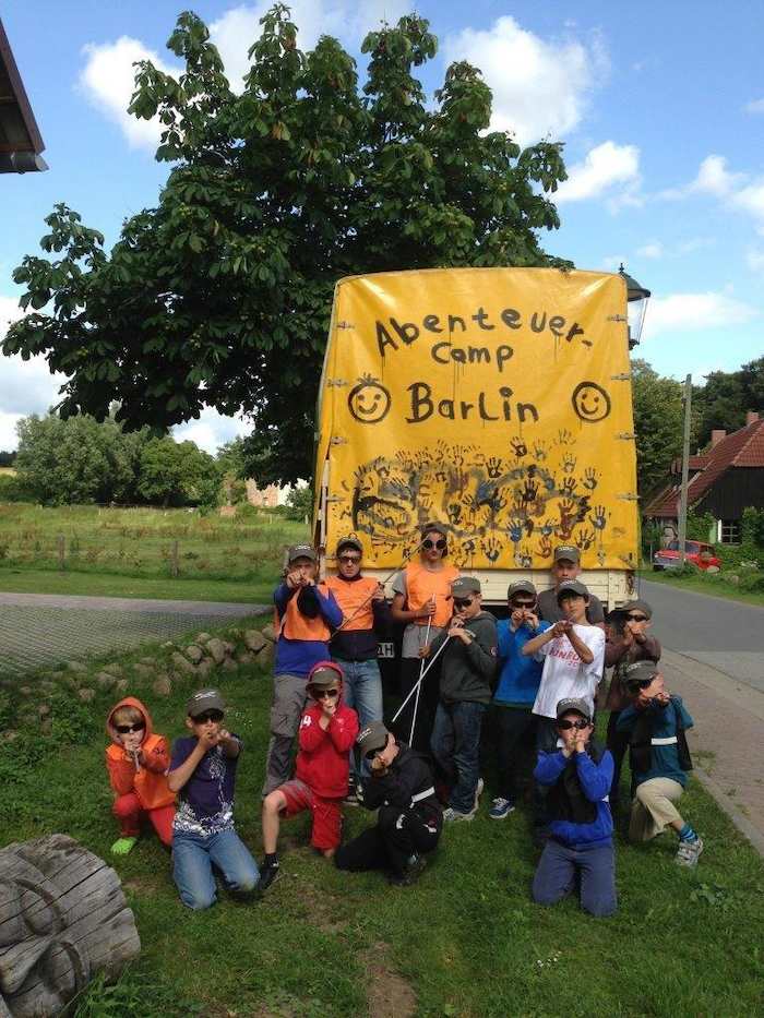 Kinder sitzen vor einem Banner während der Ferienbetreuung
