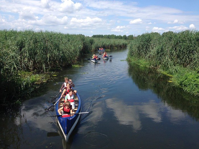 Im Ferienlager paddeln die Kids mit ihren Kanus einen Fluss entlang