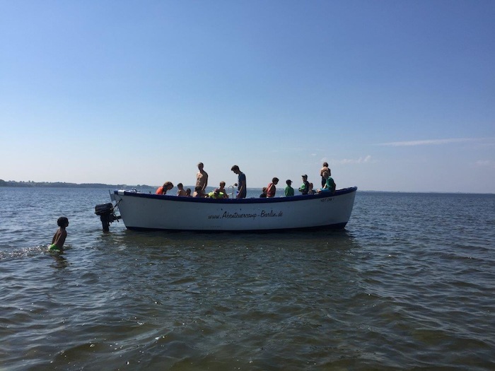 Kinder stehen auf einem Boot auf einem See während der Ferienbetreuung