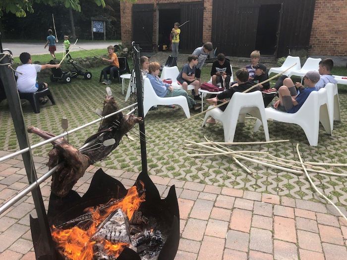 Kinder sitzen im Ponycamp neben dem Lagerfeuer in einem Stuhlkreis