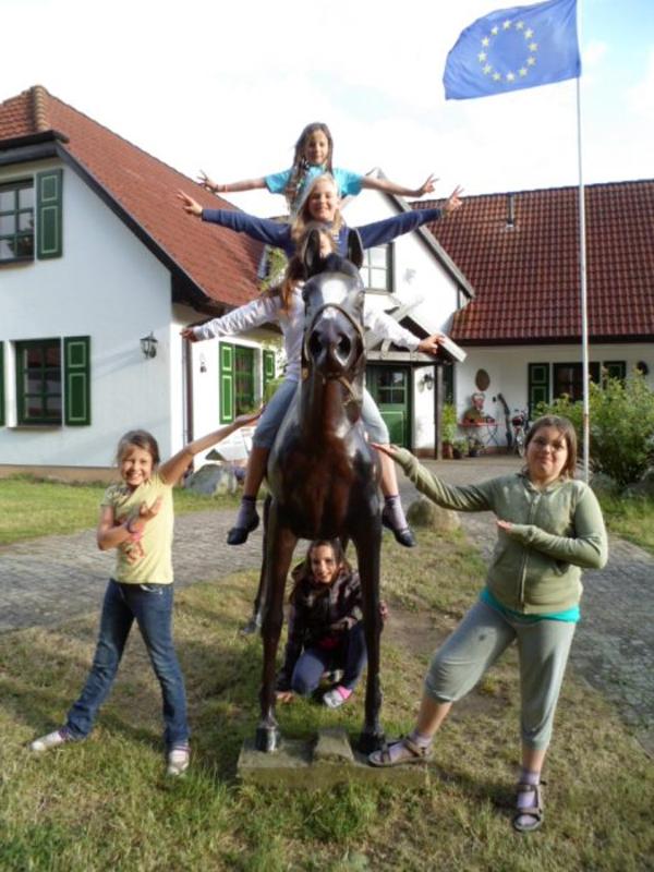 Kinder haben draußen bei einer Statue während der Ferienbetreuung Spaß