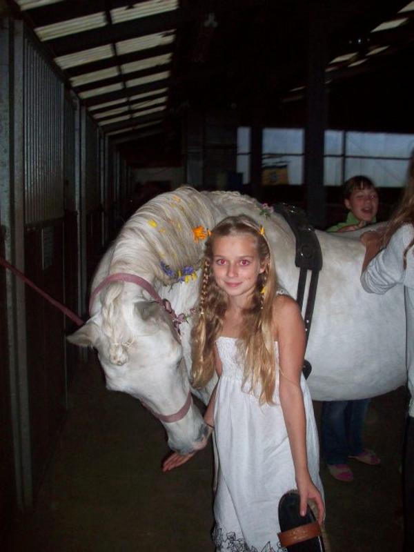 Ein Mädchen steht neben einem weißen Pferd während der Ferien Ponyhof