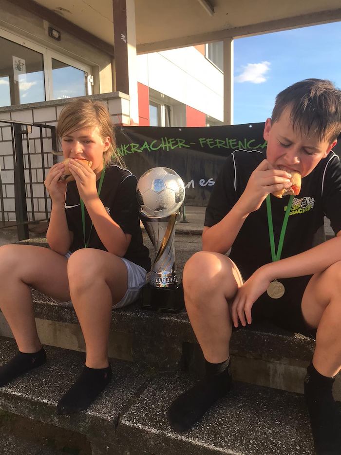 Teilnehmer eines Fußballcamps essen Burger