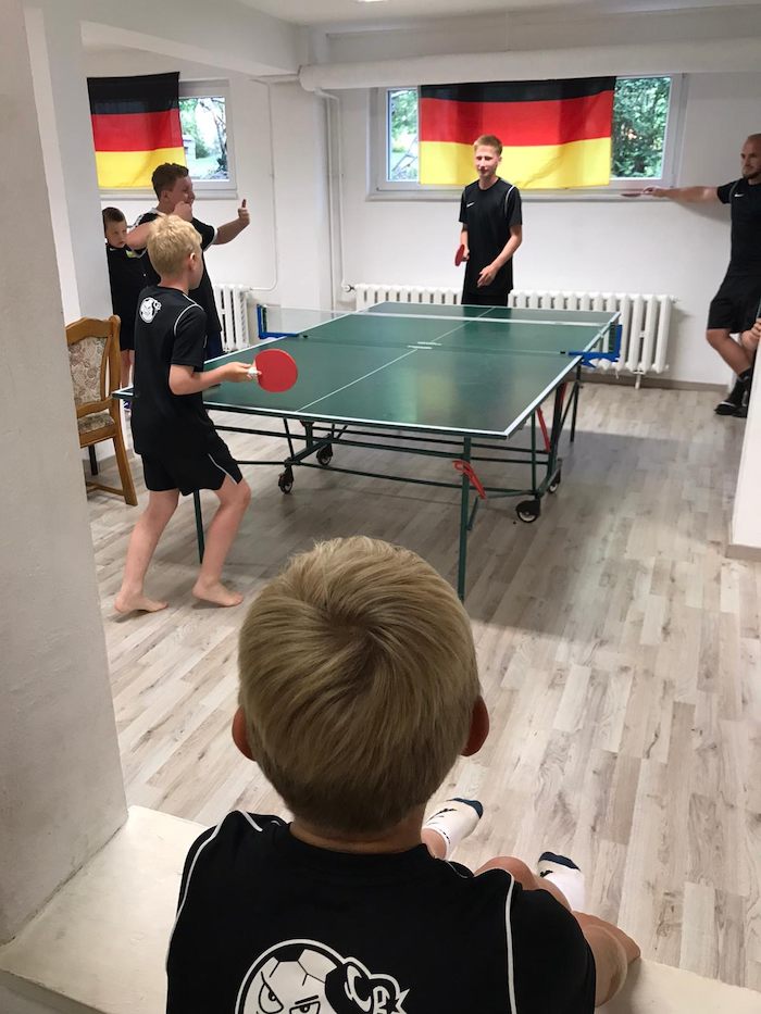 Teilnehmer eines Fußballcamps spielen Tischtennis
