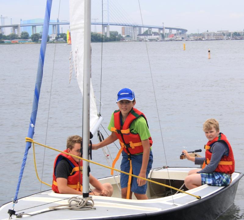 Drei Kinder sind im Segelcamp zusammen auf einem Boot.