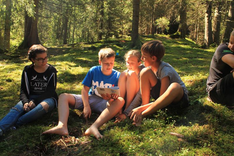 Teilnehmer eines Kindersprachkurses sitzen im Wald