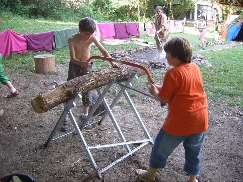 Zwei Jungs sägen einen Baumstamm in den Kinderferien.