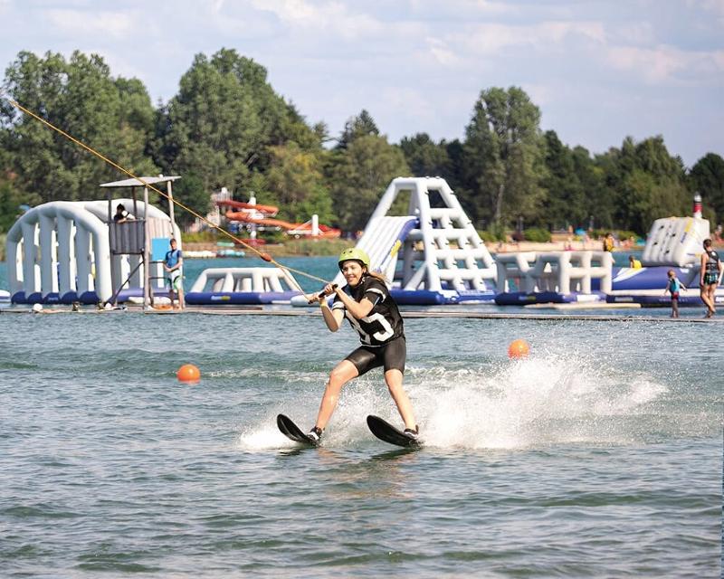 Ein Mädchen eines Wakeboard-Camps fährt übers Wasser
