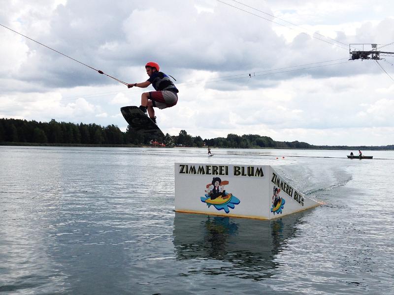 Ein Teilnehmer eines Wakeboard-Camps springt über eine Schanze