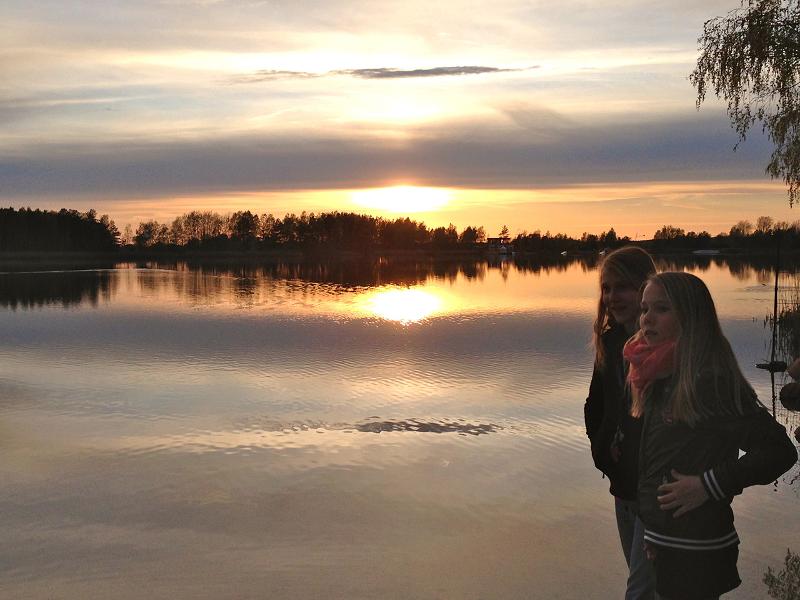 Mädchen eines Wakeboard-Camps stehen bei Sonnenuntergang am See