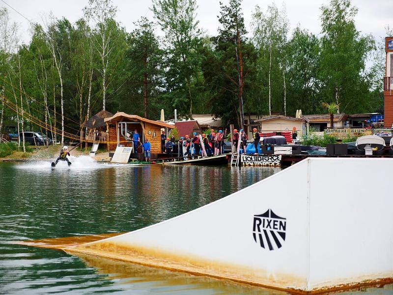 Teilnehmer eines eines Wakeboard-Camps schauen einem Jungen zu
