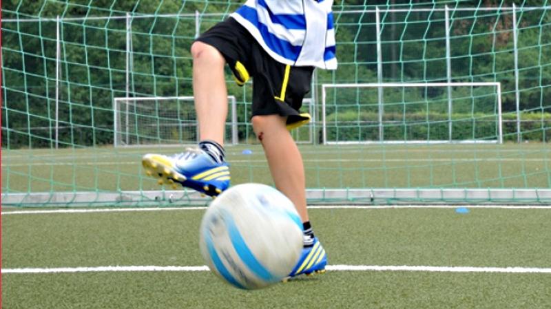 Beim Fußballcamp passt ein Junge den Ball