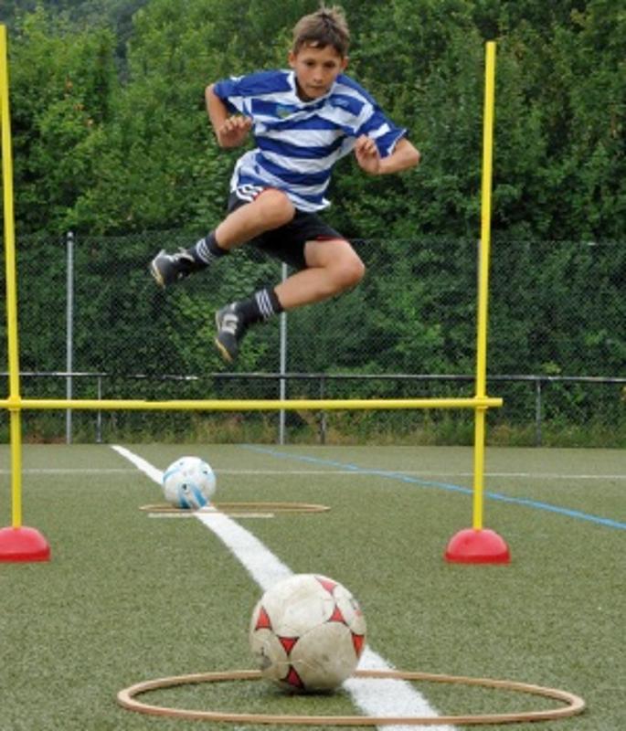 Ein Junge springt bei einer Olympiade im Fußballcamp über ein Hindernis