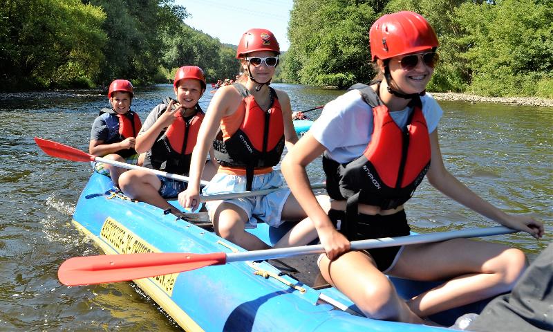 Vier Freunde sitzen im Abenteuer-Camp in einem Kanu während sie über den Fluss gleiten.