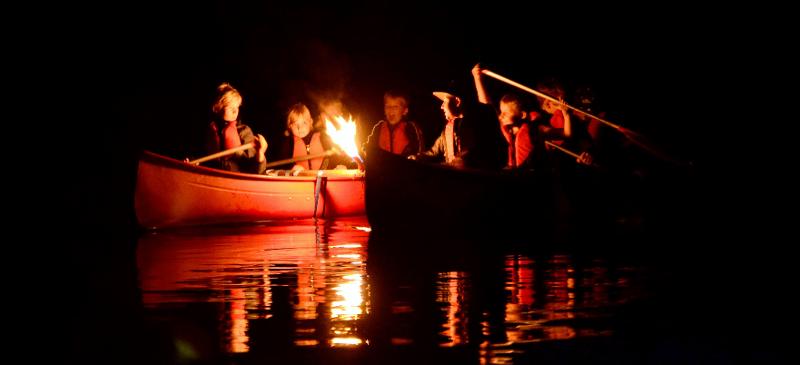 Im Abenteuer Ferienlager sind die Kids im Kanu bei Nacht auf dem Fluss unterwegs.
