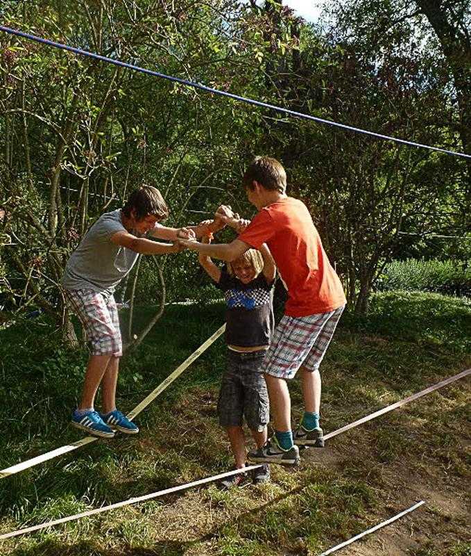 Drei Jungs haben Spaß im Abenteuer-Camp beim Balancieren auf eines Slack-Line.
