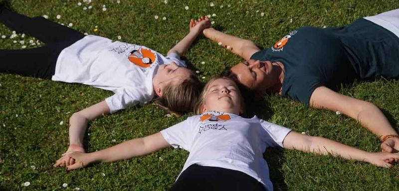 Drei Kinder liegen Kopf an Kopf im Ferienprogramm Kassel