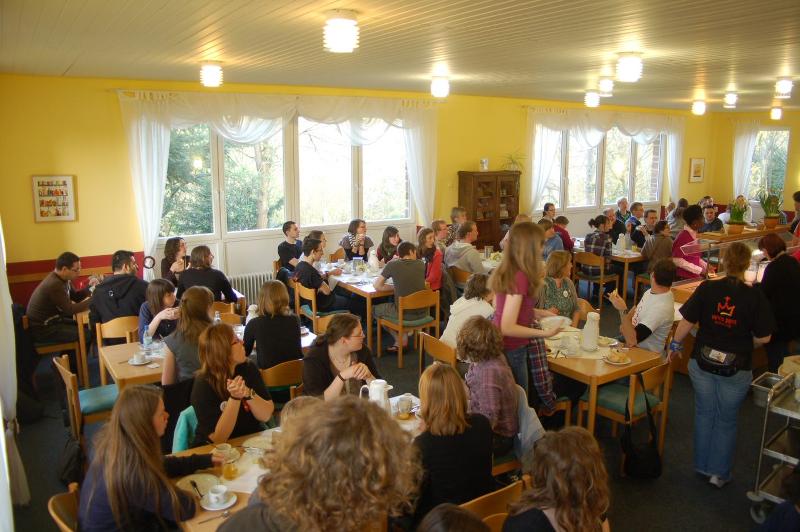 Viele Kinder sind versammelt und sitzen an verschieden Tischen in kleinen Gruppen zusammen und essen zusammen bei den Osterferien in der Jugendherberge 