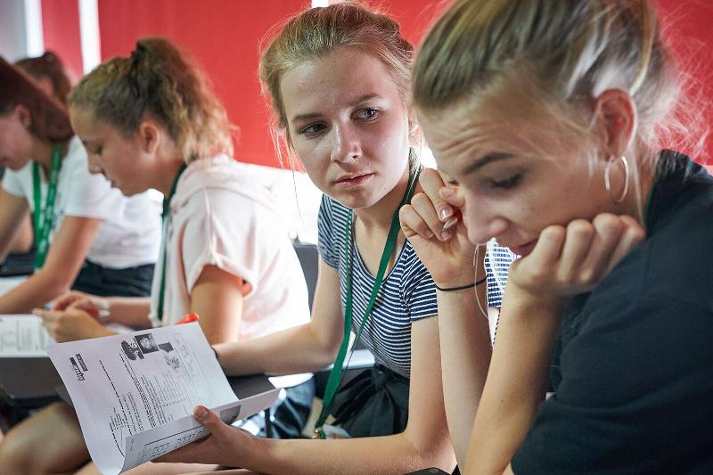 Zwei Mädchen sitzen sich mit Lernmaterial im Englischcamp Pfingstferien gegenüber