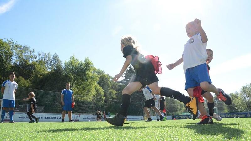 Kinder einer Fußball-Schule Ferien machen Schwänzchen Fangen