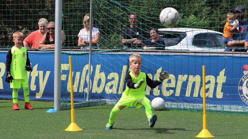 Ein Junge einer Fußball-Schule Ferien versucht einen Ball zu fangen