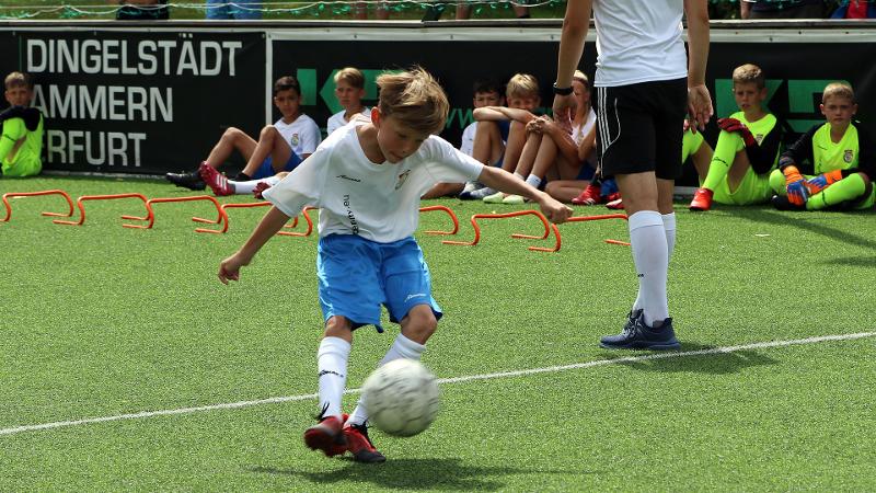 Ein Junge einer Fußball-Schule Ferien nimmt einen Ball an