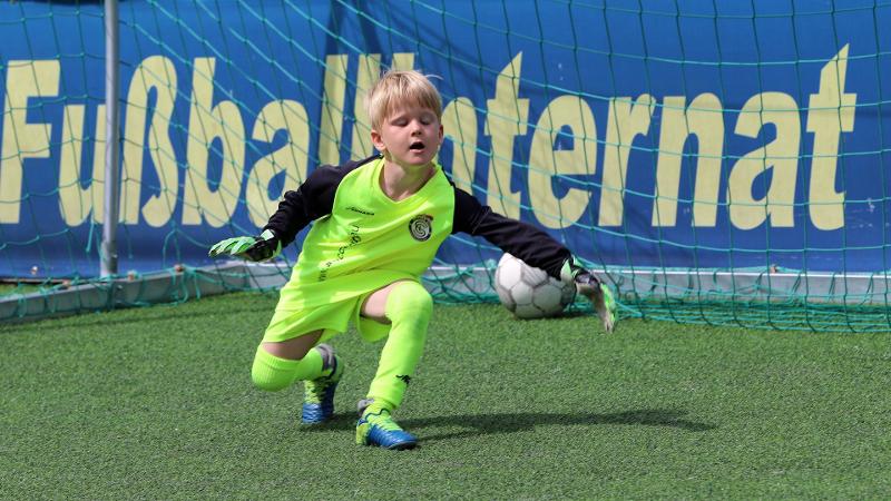 Ein Junge einer Fußball-Schule Ferien fällt ins Tor