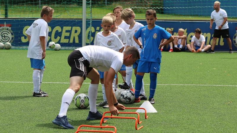 Jungs einer Fußball-Schule Ferien machen Hürdenlauf