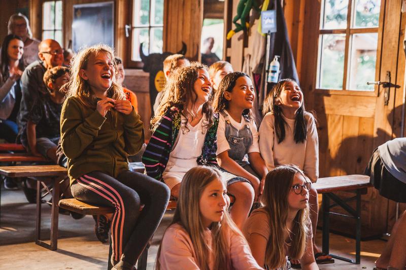 Die Kinder des Osterferienprogramms sitzen auf einer Bank und lachen gemeinsam