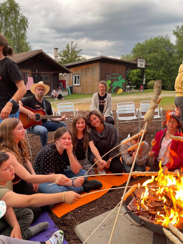 Teilnehmer vom Ferienangebot Bayern sitzen um ein Lagerfeuer
