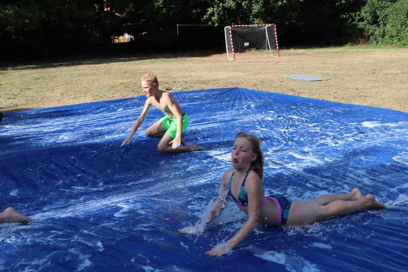 Ein Mädchen eines Handball Camps rutscht über eine Wasserfolie