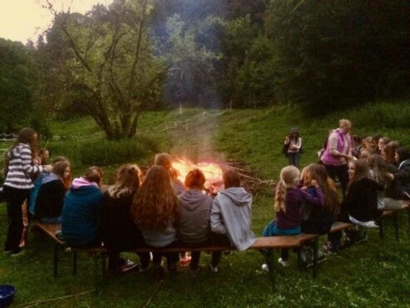 Kinder der Reiterferien für Kinder sitzen am Lagerfeuer
