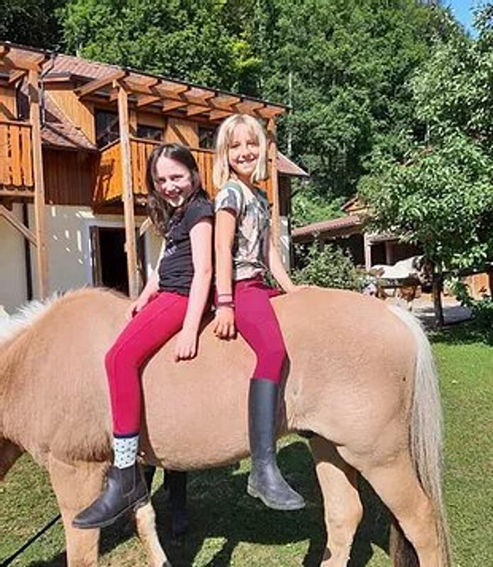 Kinder der Reiterferien für Kinder sitzen zusammen auf einem Pferd