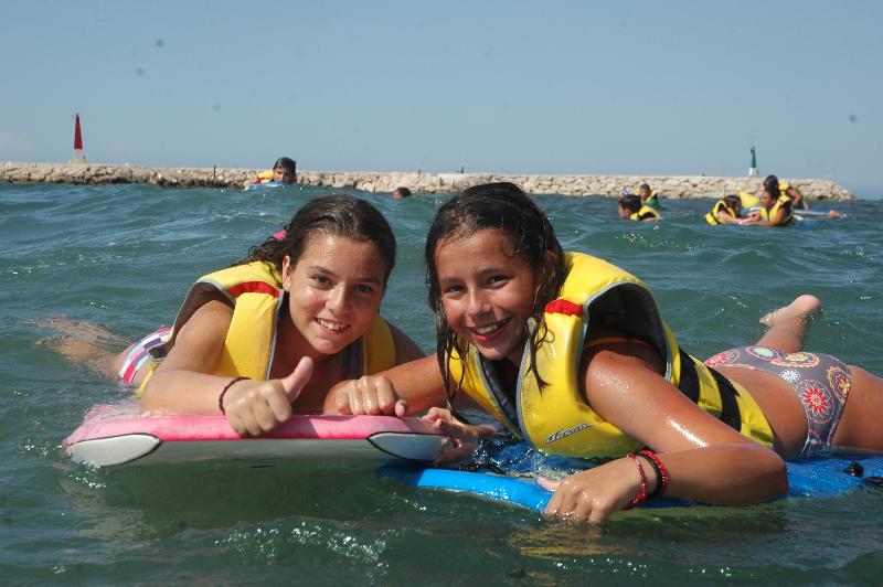 Mädchen der Sprachreise Frankreich mit Surfen Deutschland liegen im Wasser