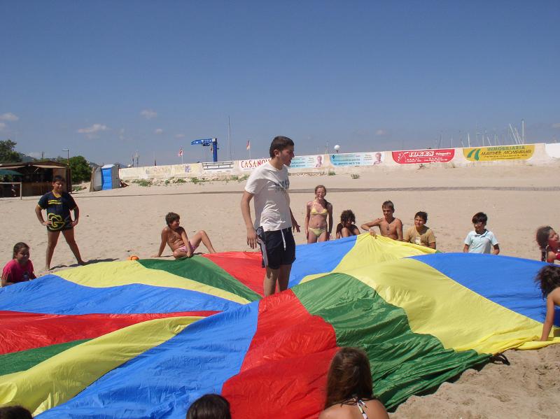 Teilnehmer eines Feriencamps am Wasser spielen mit einem Tuch
