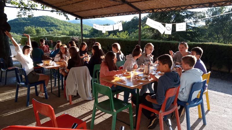 Ein Sprachcamp frühstückt gemeinsam bei schönem Wetter außen auf einer Terrasse