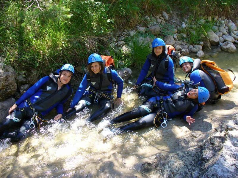 Eine kleine Gruppe sitzt glücklich und gemütlich im Wasser beim Canyoning