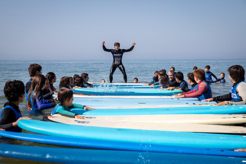 Die Teilnehmer stehen im Wasser und reihen im Surf Camp Portugal ihre Surfbretter aneinander