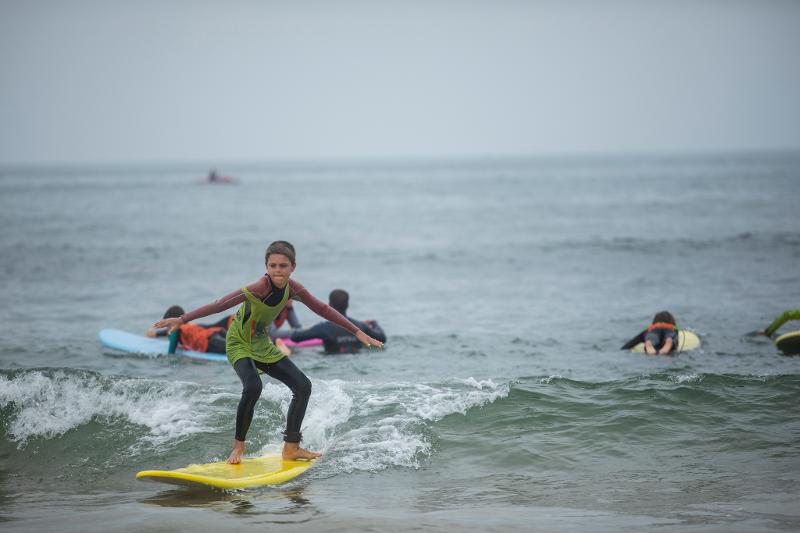 Teilnehmer eines Surfcamps für Kinder reiten Wellen