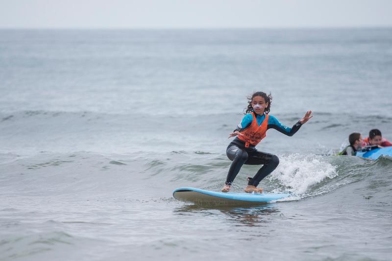 Teilnehmer eines Surfcamps surfen im Wasser