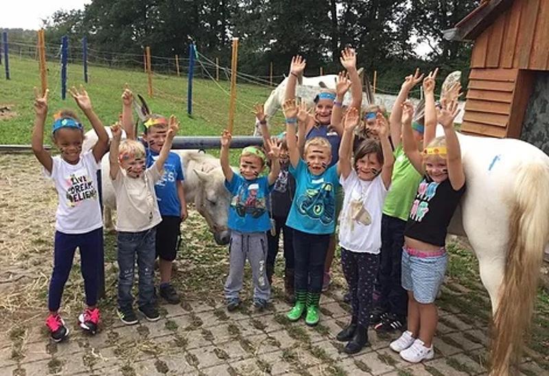 Kinder der Reiterferien Sachsen stehen vor einem Pony und jubeln.