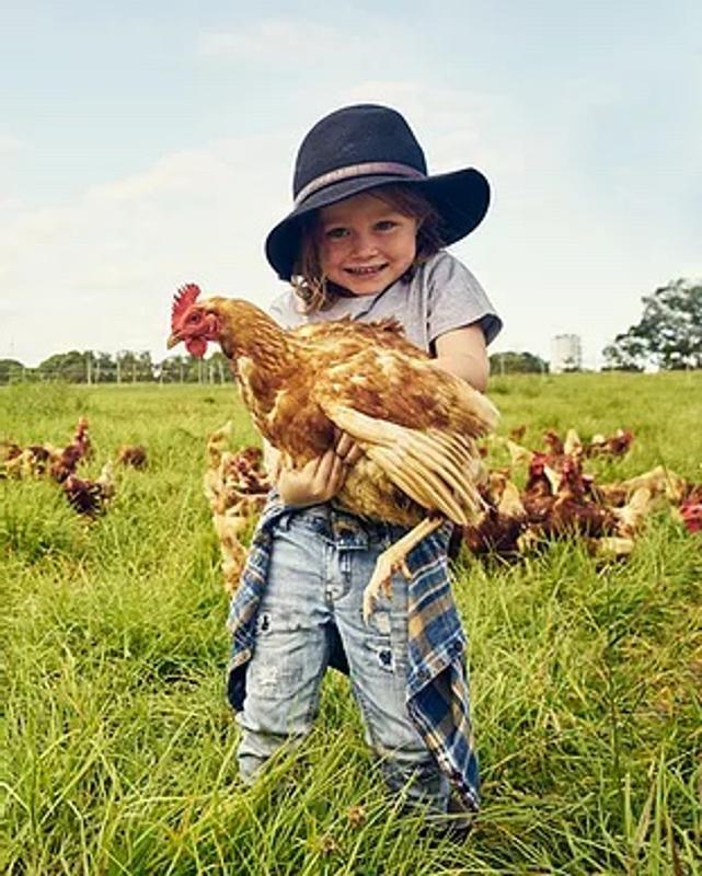 Eine Teilnehmerin der Ferienfreizeiten Koblenz hat ein Huhn auf dem Arm. 