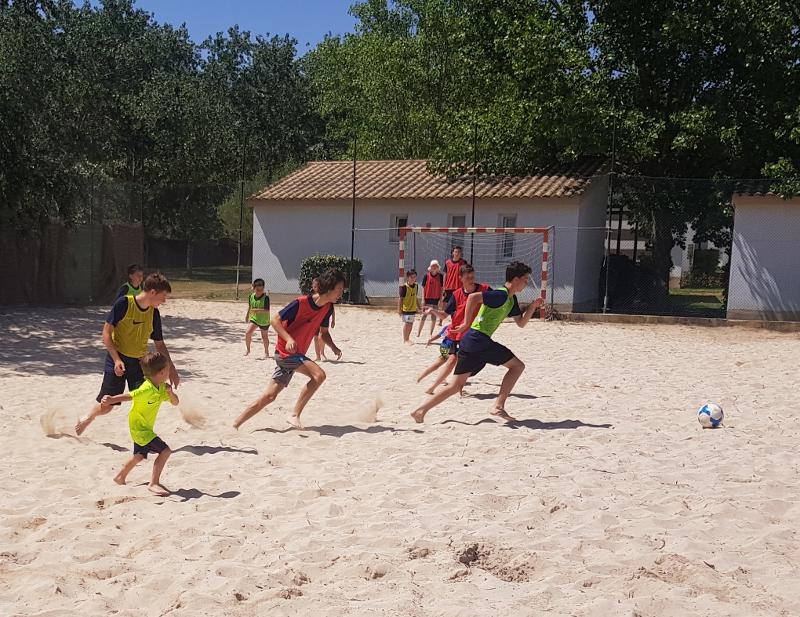 Kinder eines Englischcamps spielen Beachvolleyball