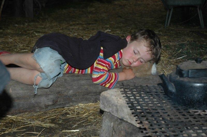 Ein Junge eines Abenteuer Forschercamps schläft im Stroh